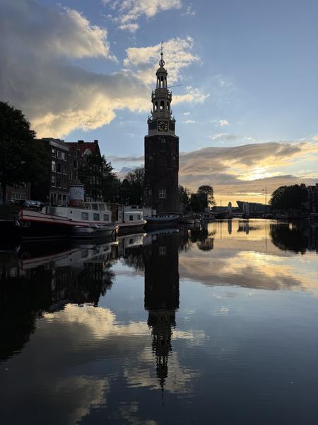 This beautiful photo captures the iconic Montelbaanstoren tower reflecting perfectly in the calm waters of the Oudeschans canal in Centrum, Amsterdam